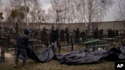 Pekerja membawa jenazah orang yang ditemukan tewas ke sebuah pemakaman di Bucha, pinggiran Kyiv, Ukraina, Selasa, 5 April 2022. (Foto: AP)