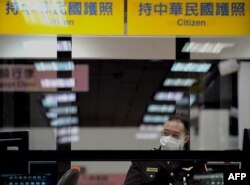 FILE - An immigration officer looks at arriving passengers at the Sungshan airport in Taipei, Taiwan, May 2, 2009.