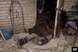 지난 5일 우크라이나 수도 크이우(러시아명 키예프) 외곽 도시 부차의 주택 출입문에서 발견된 노년 여성 사체 곁을 개가 지키고 있다.
