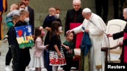 El Papa Francisco sostiene bandera ucraniana que le fue enviada desde la ciudad de Bucha, donde murieron a quemarropa personas atadas y apareción una fosa común, mientras se encuentra con niños ucranianos que huyen de la invasión rusa de Ucrania, 6 de abril de 2022. 