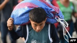 A Honduran migrant boy carries a bag as he takes part in a caravan heading to the US on the road linking Ciudad Hidalgo and Tapachula, Chiapas state, Mexico, Oct. 21, 2018. 