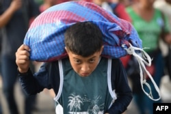 A Honduran migrant boy carries a bag as he takes part in a caravan heading to the US on the road linking Ciudad Hidalgo and Tapachula, Chiapas state, Mexico, Oct. 21, 2018.