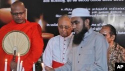 Ulama Islam Sri Lanka, menyalakan lilin dan didampingi seorang bhiksu Budha, kiri, pendeta Hindu, kanan, dan uskup Kristen, dalam sebuah acara solidaritas dengan seluruh korban dari serangan Hari Paskah, Minggu, di Kolombo, Sri Lanka, Minggu, 28 April 2019 (foto: AP Photo/Manish