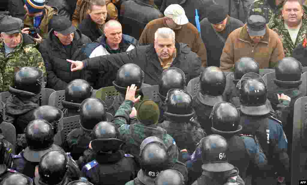 A protester argues with police in front of Ukrainian Parliament in Kyiv. Lawmakers in the government-controlled chamber overwhelmingly adopted a bill dropping the country&#39;s non-aligned status - a classification given to states such as Switzerland which refuse to join military alliances and thus play no part in wars.