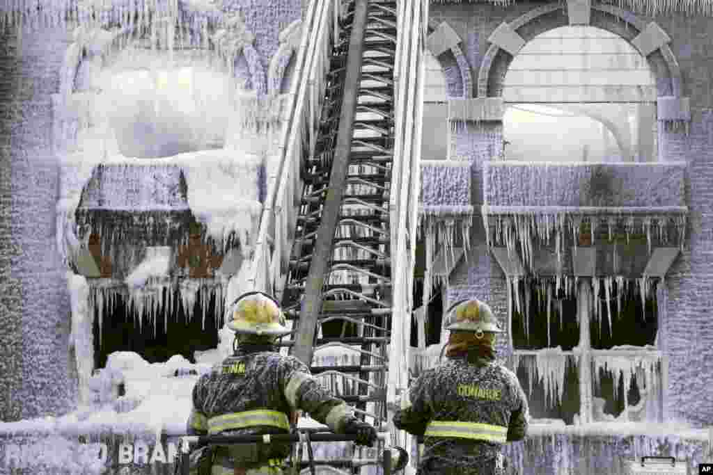 Petugas pemadam kebakaran berusaha memadamkan api di kota Philadelphia, Pennsylvania dalam cuaca dingin ekstrim hingga air yang disemprotkan untuk memadamkan api segera menjadi beku.