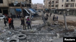 People inspect a site hit by airstrikes at a parking garage in the rebel-held city of Idlib, Syria, Jan. 18, 2017. 