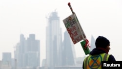 FILE - A climate change activist holds a placard at Waterloo Bridge during the Extinction Rebellion protest in London, Britain, April 16, 2019. Some activists of the group were arrested Tuesday while staging a protest at the International Criminal Court in the Hague.