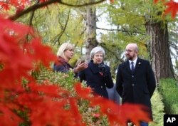 Britain's Prime Minister Theresa May, Belgian Prime Minister Charles Michel, right, and Liz Sweet, Director, External Relations, Western Europe Area, Commonwealth War Graves Commission, left, walk through the St Symphorien Military Cemetery in Mons, Belgium, Nov. 9, 2018.