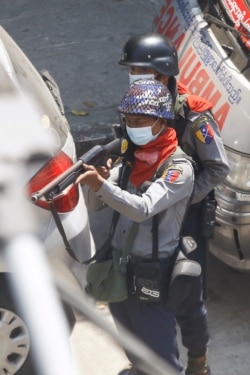 Riot Police aim his gun towards protesters during a demonstration in Yangon, Myanmar, March 7, 2021.
