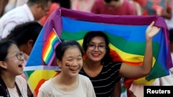 Seorang perempuan membawa bendera pelangi di acara pawai tahunan 'gay pride' Singapura, "Pink Dot" di Singapura, 1 Juli 2017. (Foto: dok).