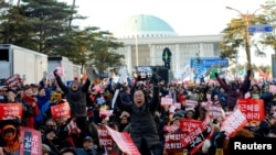 Warga bereaksi di depan Majelis Nasional di Seoul, Korea Selatan, usai disahkannya hasil pengambilan suara pemakzulan Presiden Korea Selatan Park Geun-hye, dengan membawa spanduk bertuliskan "Dakwa Park Geun-hye", 9 Desember 2016 (Foto: News1 via REUTERS).