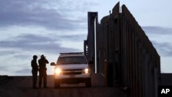FILE - United States Border Patrol agents stand by a vehicle near one of the border walls separating Tijuana, Mexico and San Diego, in San Diego, Nov. 21, 2018.