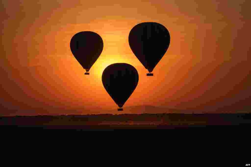 Hot-air balloons fly up with tourists at sunrise in the Masai Mara game reserve in Kenya.