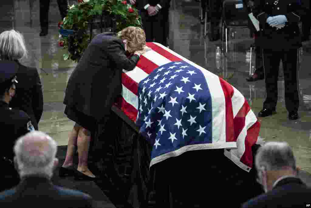 Former Sen. Elizabeth Dole, rests her head on the casket of her husband, former Sen. Bob Dole of Kansas, in state in the Rotunda of the U.S. Capitol.