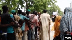 People line up along a sidewalk in front of Hajia Hawa as Yamirai Hawa passes out vouchers for free food,Maiduguri, Nigeria, Sept. 2016. (Photo: C. Oduah)