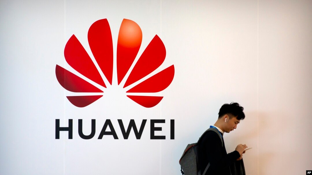 一名男子站在中國科技公司華為的廣告牌旁使用智能手機（2019年10月31日）。