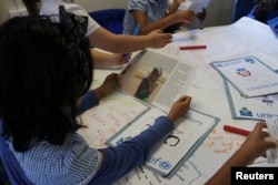 FILE - Primary school children take part in classroom lesson at Norbury School in Harrow, London, Britain, July 15, 2016.