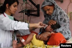 A medic (L) attends to Shakeel Ahme, 2, suffering from measles, at the Mayo Hospital in Lahore May 27, 2013. Measles, a highly contagious viral disease, has killed 260 people across Pakistan in 2013 so far, with nearly 11,000 cases reported, according to