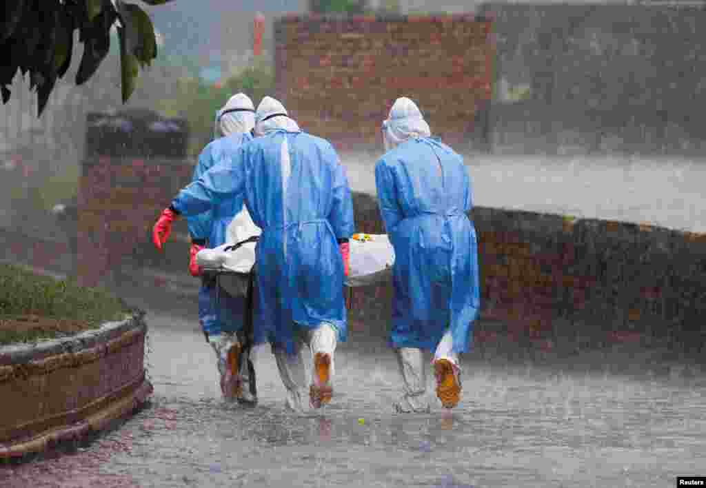 Members of Nepal Army wearing personal protective equipment (PPE) carry the body of a person, who died from the COVID-19, in the rain at the crematorium in Kathmandu.