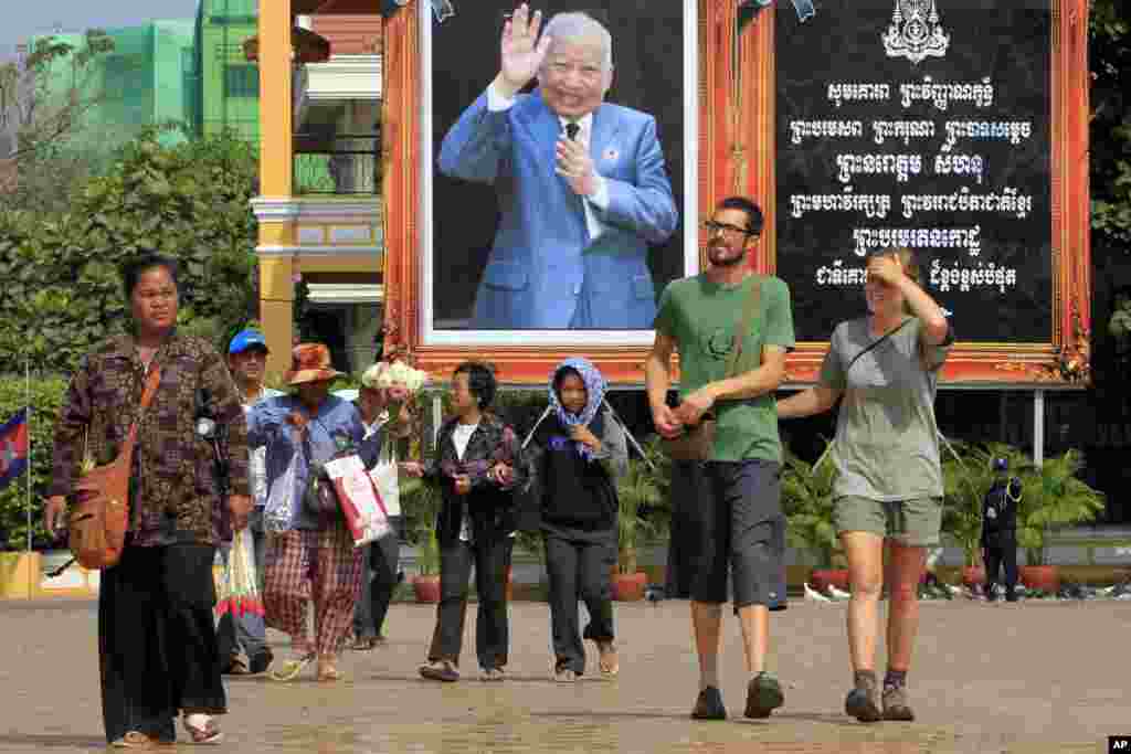 Foreign tourists, right, walk in front of Cambodia&#39;s late King Norodom Sihanouk portrait ahead of his funeral, Thursday, Jan. 31, 2013, in Phnom Penh, Cambodia. The body of Sihanouk who died on Oct. 15, 2012 at age 89, is scheduled to be cremated on Feb. 4, 2013. (AP Photo/Heng Sinith)