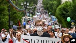 A man holds a poster reading "Putinizm" during an unsanctioned protest in support of Sergei Furgal, the governor of the Khabarovsk region, who was interrogated and ordered held in jail for two months, in Khabarovsk, Russia, July 25, 2020. 