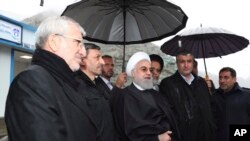 Iranian Presidency, President Hassan Rouhani, center, speaks while viewing a new highway, Feb. 25, 2020. Rouhani sought to reassure the nation in a speech on Tuesday, calling the new coronavirus an "uninvited and inauspicious passenger." 