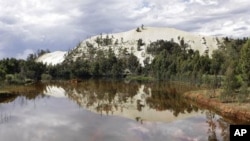 A gold mine dump is reflected in toxic water in Randfontein, west of Johannesburg, South Africa, January 26, 2011.