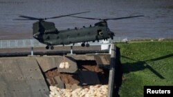 A Chinook helicopter drops sand bags on top of the dam after a nearby reservoir was damaged by flooding, in Whaley Bridge, Britain, Aug. 2, 2019.