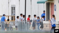 FILE - In this June 20, 2018, file photo, immigrant children walk in a line outside the Homestead Temporary Shelter for Unaccompanied Children, a former Job Corps site that now houses them in Homestead, Florida.