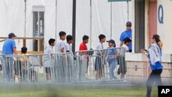 FILE - Immigrant children walk in a line outside the Homestead Temporary Shelter for Unaccompanied Children, a former Job Corps site that now houses them in Homestead, Florida, June 20, 2018.