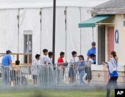 FILE - In this June 20, 2018, file photo, immigrant children walk in a line outside the Homestead Temporary Shelter for Unaccompanied Children, a former Job Corps site that now houses them in Homestead, Florida.