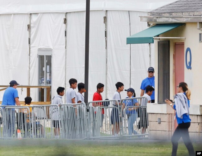 FILE - In this June 20, 2018, file photo, immigrant children walk in a line outside the Homestead Temporary Shelter for Unaccompanied Children, a former Job Corps site that now houses them in Homestead, Florida.