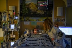 Tiffany Jackson comforts her son Adrian James, 2, who tested positive for the coronavirus disease (COVID-19), as he breathes with assistance from a ventilator at SSM Health Cardinal Glennon Children's Hospital in St. Louis, Missouri, on October 5, 2021.