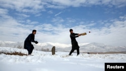 FILE - Afghan men play cricket on a field covered in snow on the outskirts of Kabul, Afghanistan, Dec. 16, 2017. 