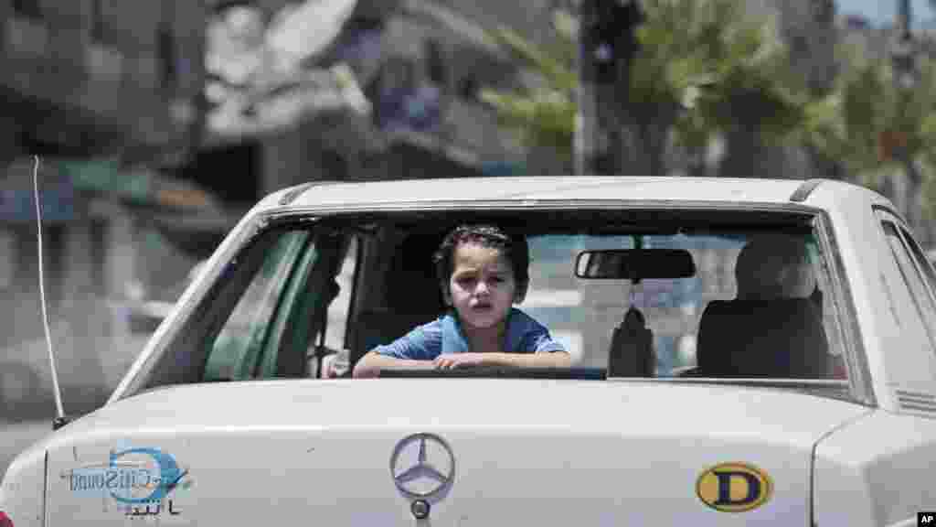 A Palestinian boy looks outside a car by the rubble of a house hit by an Israeli strike during the Gaza war in Gaza City, Aug. 10, 2014. 