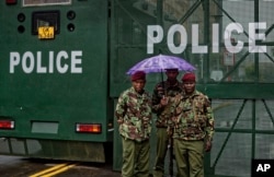 Kenyan police officers stand in the rain by a barrier blocking off vehicle and pedestrian access, amid tight security outside the Supreme Court in Nairobi, Kenya, Nov. 14, 2017.