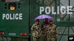 Des policiers kényans se tiennent sous la pluie près d'une barrière bloquant l'accès des véhicules et des piétons devant la Cour suprême à Nairobi, au Kenya, le 14 novembre 2017.