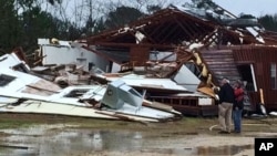 People survey damage to a business off Mississippi Highway 18 in Sylverana, Miss., Feb. 15, 2016, after severe weather affected south Mississippi. 