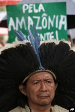 Indigenous leader Kreta Kaingang stands in front of a sign that reads in Portuguese "For the Amazon. Urgent!" during a protest against right-wing presidential candidate Jair Bolsonaro, in front of the Ministry of Environment in Brasilia, Brazil, Oct. 19