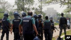 Bangladeshi policemen watch as paramilitary soldiers try to flush out Islamist radicals in the city of Sylhet, March 26, 2017. 