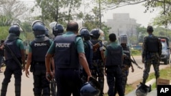 FILE - Bangladeshi policemen watch as paramilitary soldiers try to flush out Islamist radicals who have holed up in a building with a large cache of ammunition in the city of Sylhet, March 26, 2017. 