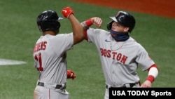 FILE - Boston Red Sox third baseman Rafael Devers gets an elbow bump from the batboy (right) after hitting a two-run home run at Tropicana Field, Sept. 10, 2020, St. Petersburg, Florida. (Reinhold Matay-USA TODAY Sports)