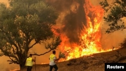 Men attempt to put out a fire in Iboudraren village, east of Algiers, Algeria, Aug. 12, 2021. 