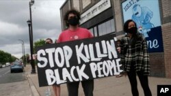 Manifestantes protestan en el lugar en que George Floyd, un ciudadano afroamericano, falleció durante su arresto a manos de cuatro agentes de la policía.