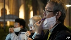 FILE - People with masks blow whistles during a vigil for Chinese doctor Li Wenliang, in Hong Kong, Feb. 7, 2020. The doctor, who was reprimanded for warning about China's new virus, died from the disease.