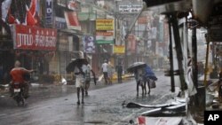 People walk past fallen sign boards and other trash caused by heavy winds in Pondicherry, India, December, 30, 2011.
