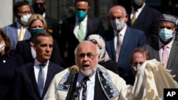 FILE—Rabbi Abraham Cooper, center, of the Simon Wiesenthal Center, speaks in front of civic and faith leaders outside City Hall, Thursday, May 20, 2021, in Los Angeles.