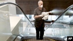 In this April 2020 photo provided by Marriott, a Marriott associate using an electrostatic sprayer to clean public areas at the Brooklyn Bridge Marriott in New York. (Marriott via AP)