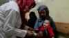 An Afghan woman holds her sick daughter as a nurse treats her in the malnutrition ward of the Indira Gandhi Children's Hospital in Kabul, Afghanistan, Feb. 24, 2022. 