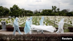 Workers wearing personal protective equipment (PPE) carry the body of a victim of the coronavirus disease (COVID-19) at a cemetery, in Batu Caves, Malaysia Jan. 27, 2021. 
